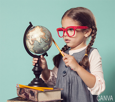 photo of a young girl pointing to globe with a pencil