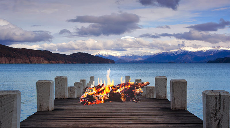 Photo of a dock on a bay with a bonfire on it.
