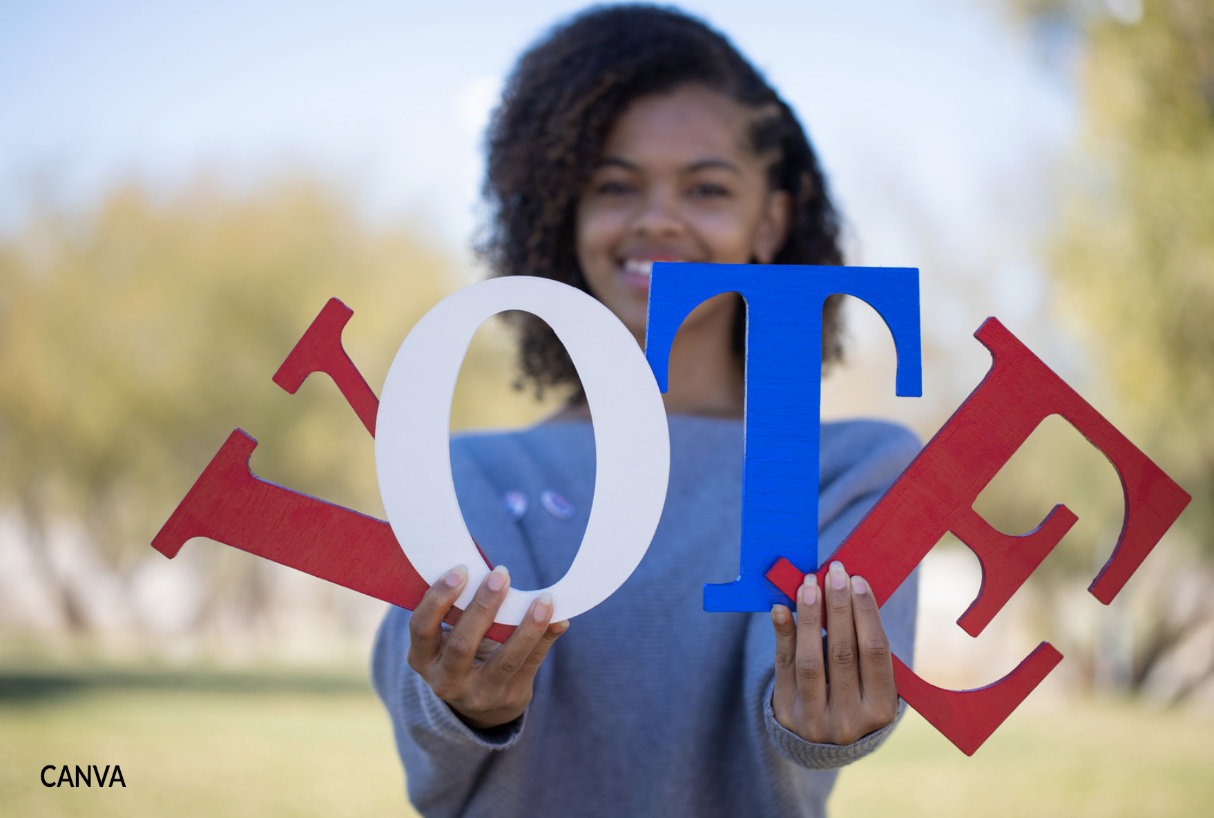 Photo of young woman holding the letters V O T E